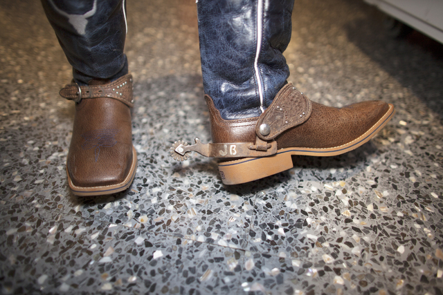 Jake Beutler shows off his cowboy boots with his initials on them at the National Finals Rodeo ...