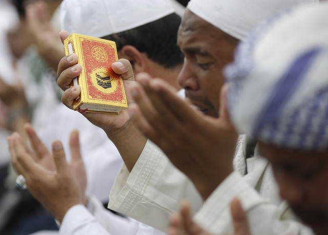 A Muslim man hods a Quran as he prays during a rally against Jakarta's minority Christian Governor Basuki "Ahok" Tjahaja Purnama who is being prosecuted for blasphemy, at the National Monument in  ...