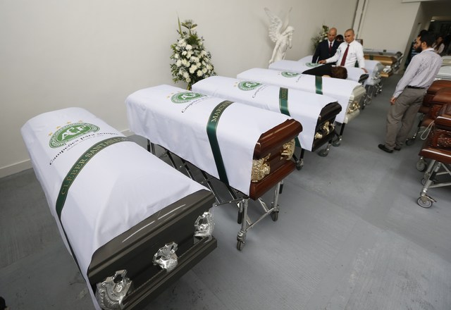 Funeral employees place white sheets with a Chapecoense soccer team logo on caskets containing the remains of team members, in Medellin, Colombia, Thursday, Dec. 1, 2016. Forensic authorities say  ...