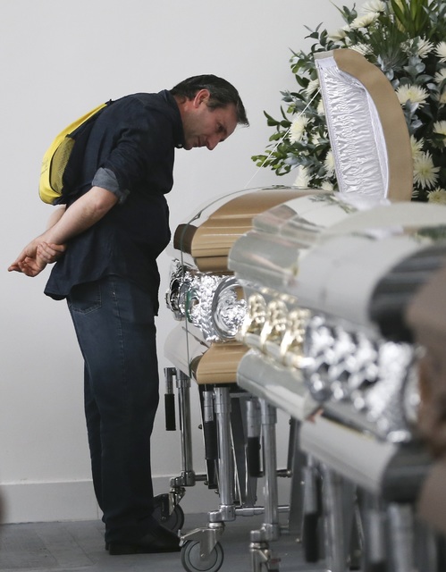 Roberto D'marchi gazes into the casket containing the remains of his cousin of Nilson Folle Jr., a victim of the Colombian air tragedy, in the parking garage of the San Vicente funeral home in Med ...
