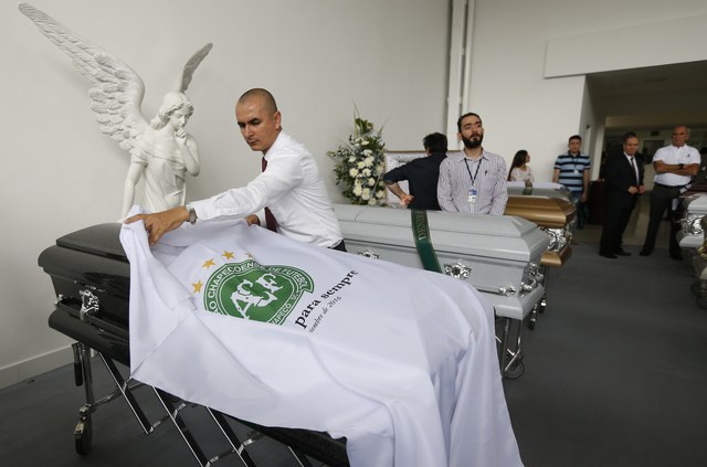 A funeral employee places a white sheet with a Chapecoense soccer team logo over a casket containing the remains of a team member, in Medellin, Colombia, Thursday, Dec. 1, 2016. Forensic authoriti ...
