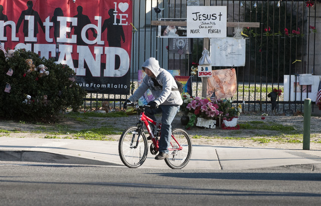 A cyclist passes memorial items displayed at the Inland Regional Center, the site of last year's terror attack, in San Bernardino, Calif., Thursday Dec. 1, 2016. Friday will mark the one year anni ...