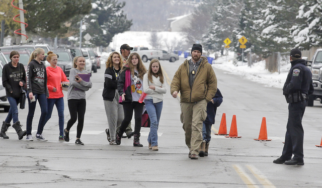 A police officer escorts students down the street following a school lockdown at Mueller Park Junior High after a student fired a gun into the ceiling Thursday, Dec. 1, 2016, in Bountiful, Utah.   ...