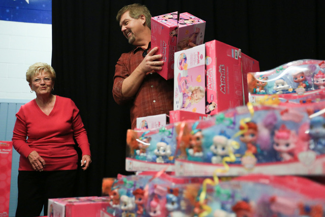 Sandy Ellis, left, and Bob Murnane, Henderson city manager, hand out gifts to students at C.T. Sewell Elementary School in Henderson on Friday, Dec. 16, 2016. The gifts were donated by Bob and San ...