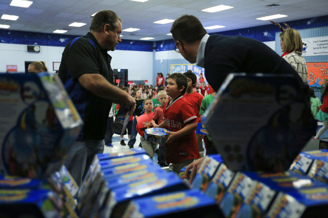 Volunteers hand out gifts to students at C.T. Sewell Elementary School in Henderson on Friday, Dec. 16, 2016. The gifts were donated by Bob and Sandy Ellis, who have donated more than 20,000 shoes ...