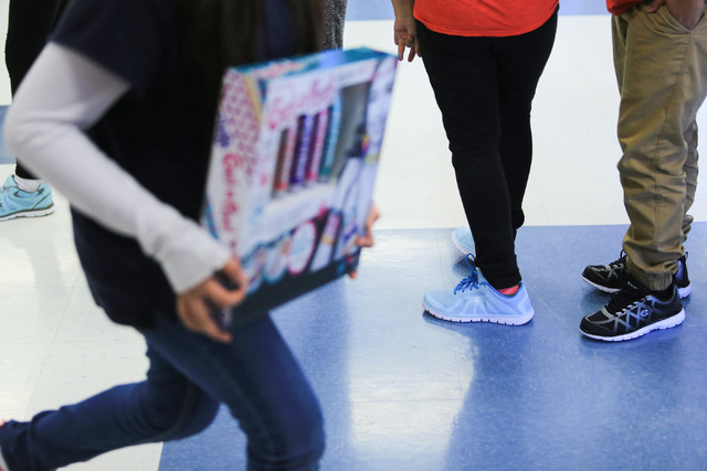 Students wear their new shoes while standing in line for gifts at C.T. Sewell Elementary School in Henderson on Friday, Dec. 16, 2016. The gifts were donated by Bob and Sandy Ellis, who have donat ...