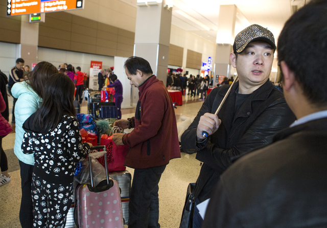 Augus, second from right, from Stream.co tour group gathers passengers from Hainan Airlines at McCarran International Airport on Friday, Dec. 2, 2016. The first nonstop flight from China arrived o ...
