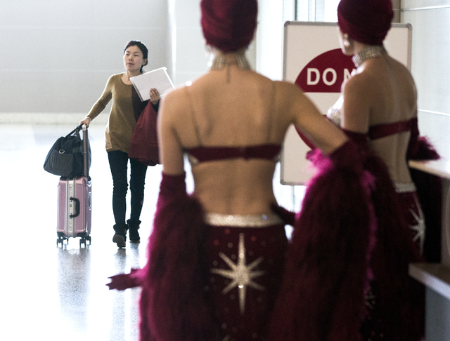 Showgirls watch a passenger from Hainan Airlines from Beijing walk in the concourse at McCarran International Airport on Friday, Dec. 2, 2016. The first nonstop flight from China arrived on Friday ...