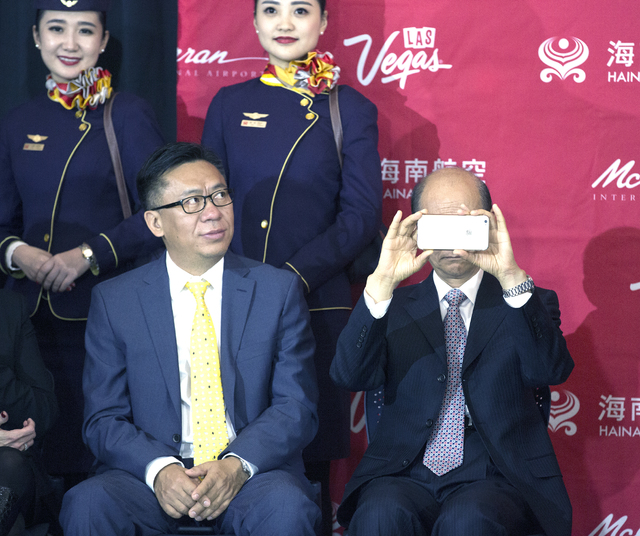 Hou Wei, second from left, senior VP of Hainan Airlines, looks on while Luo Linquan, consul general for the People's Republic of China in San Francisco,  takes a photograph during an inaugural fli ...
