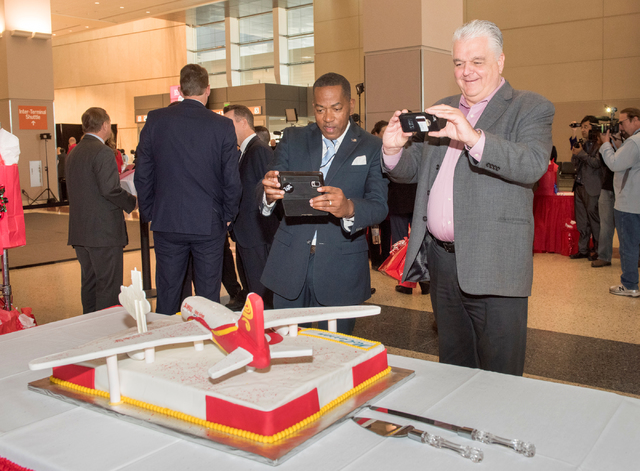 Clark County Commissioners Lawrence Weekly, left, and Steve Sisloak grab a photo of a special cake which celebrates the arrival of Hainan Airlines first flight from Beijing to McCarran Internation ...