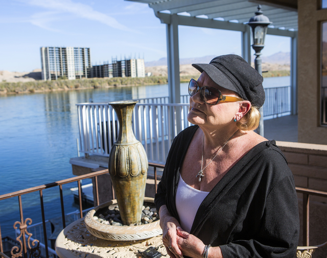Susan Martinolich stands in her porch in Bullhead City, Ariz. while the abandoned Emerald River resort tower is seen in the background on Tuesday, Dec. 6, 2016. The project has been shut down for  ...