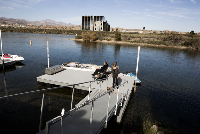Evan La-Fond, left, and his wife Marie Santa-La Fond hang out on their dock in Bullhead City, Ariz. while the abandoned Emerald River resort tower is seen in the background on Tuesday, Dec. 6, 201 ...
