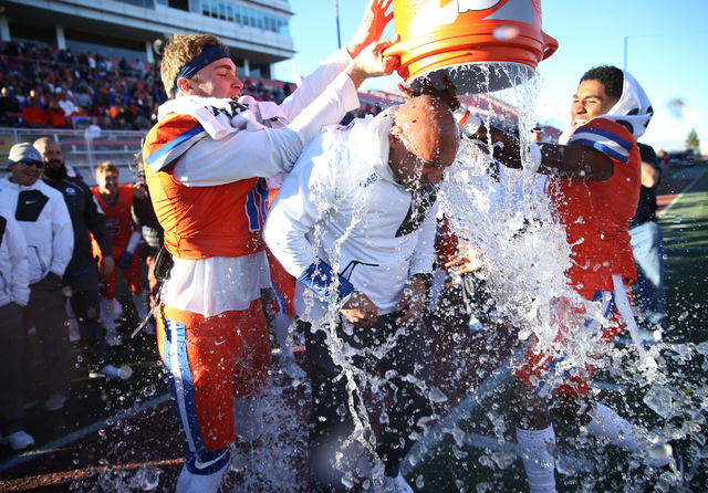 Bishop Gorman's head football coach Kenny Sanchez, center, gets a Gatorade (water) shower by his players Tate Martell (18), left, and Alex Perry (4) as the game comes to an end for a win 88-8 agai ...