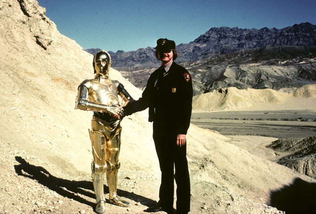 Death Valley National Monument ranger Rick McIntyre shakes hands with C-3PO during the brief 1982 location shoot for "Return of Jedi" in Death Valley's Twenty Mule Team Canyon. Portions of the ori ...