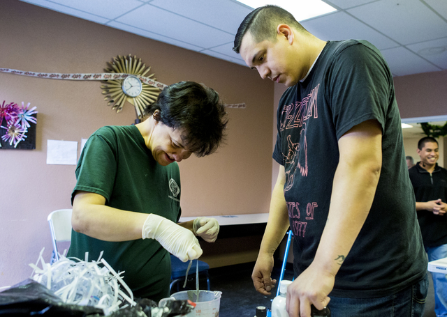 Debbie Jones, an individual at Transition Services facility, left, and Juan Jimenez, community training specialist, handmake tinsel to decorate the facility in Henderson, Thursday, Dec. 15, 2016. ...