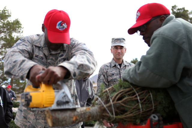 Senior Airman Adam Low, center, watches as Master Sgt. Stanley Miller, left, and Tech. Sgt. Reginald Jackson fresh cut his Christmas tree as part of the annual Christmas SPIRIT Foundation’s ...