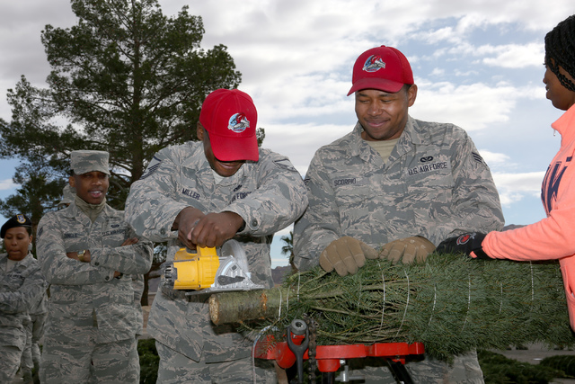 Master Sgt. Stanley Miller, left, and Senior Airman Darius Scorpio fresh cut a Christmas tree with some help from Senior Airman Brittany Davis, right, as part of the annual Christmas SPIRIT Founda ...