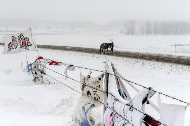 A person walks a horse past the Oceti Sakowin camp in a snow storm during a protest against plans to pass the Dakota Access pipeline near the Standing Rock Indian Reservation, near Cannon Ball, No ...