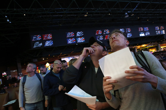 Betters who declined to give their name look at a tv screen while standing in line to place their bets at the Westgate sports book on Thursday, Jan. 26, 2017, in Las Vegas. (Christian K. Lee/Las V ...