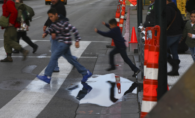 Children jump over a puddle along Fremont Street at Las Vegas Boulevard in downtown on Friday, Jan. 13, 2017. (Chase Stevens/Las Vegas Review-Journal) @csstevensphoto