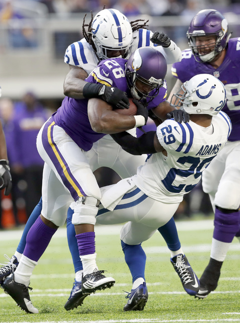 Minnesota Vikings running back Adrian Peterson (28) runs with the ball as Indianapolis Colts linebacker Erik Walden and safety Mike Adams (29)defend during the first half of an NFL football game S ...