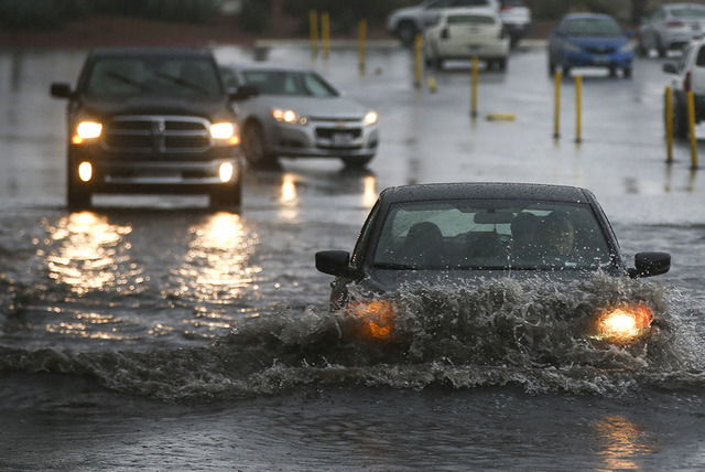 People navigate a flooded parking lot at UNLV in Las Vegas on Saturday, Feb. 18, 2017. (Chase Stevens/Las Vegas Review-Journal) @csstevensphoto