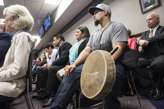 Aleczandar Guzman, a member of the Paiute Tribe, holds a hand drum while listening to officials on the Senate Government Affairs Committee discuss a resolution to replace Columbus Day with Indigen ...