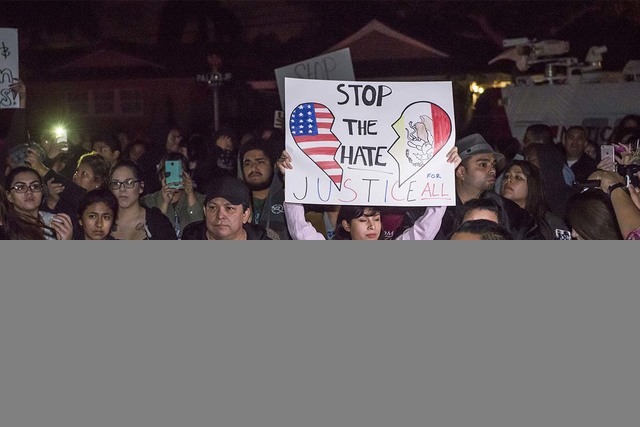 Protesters hold signs in front of an LAPD officer's home in Anaheim, California, Wednesday, Feb. 22, 2017. A Los Angeles policeman is under investigation after a video appears to show him firing a ...