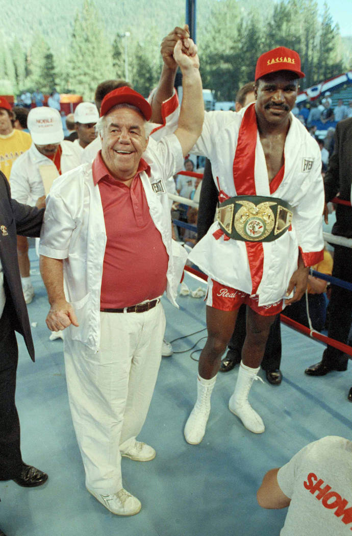 In this July 16, 1989, file photo, trainer Lou Duva raises the hand of heavyweight boxing champ Evander Holyfield at Lake Tahoe, Nev., the day after he defeated Brazilian Adilson Rodrigues. Duva,  ...