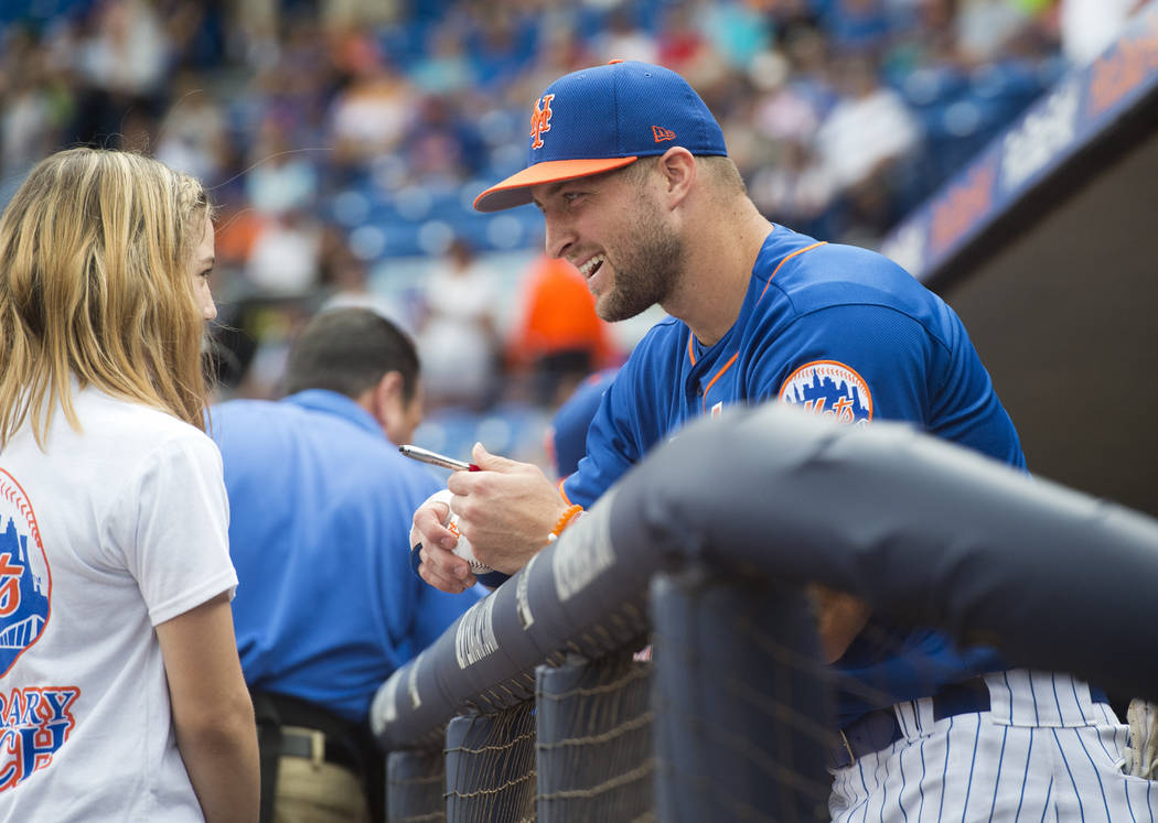 Tim Tebow signs a ball for Mackenzie Demers, 12, of Port St. Lucie, before the New York Mets played the Boston Red Sox in a spring training baseball game on Wednesday, March 8, 2017, at First Data ...