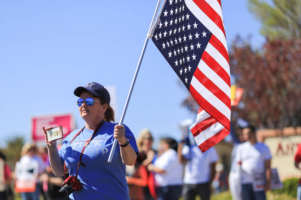 Colleen Brola, 51, carries an upside-down American flag during a protest against Sen. Dean Heller, R-Nev., who made an appearance at the Sun City Anthem Center in Henderson on Saturday, March 11, ...