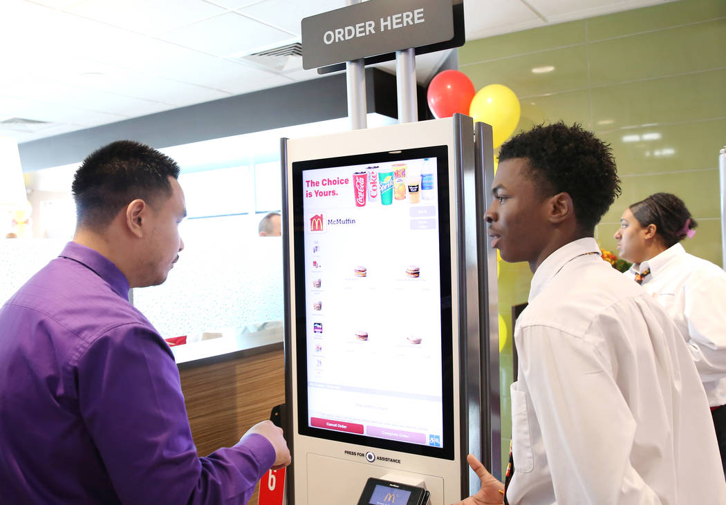 A McDonald's employee Claude Herbert, right, explains to a customer how ordering is done at a self-service kiosk on Sunset Road and Durango Drive on Wednesday, March 22, 2017, in Las Vegas. The st ...
