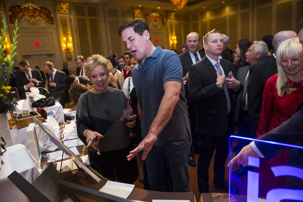 Entrepreneur Mark Cuban, center, looks at silent auction items with an attendee during the Adelson Educational Campus' 13th annual In Pursuit of Excellence Gala at The Venetian hotel-casino in Las ...