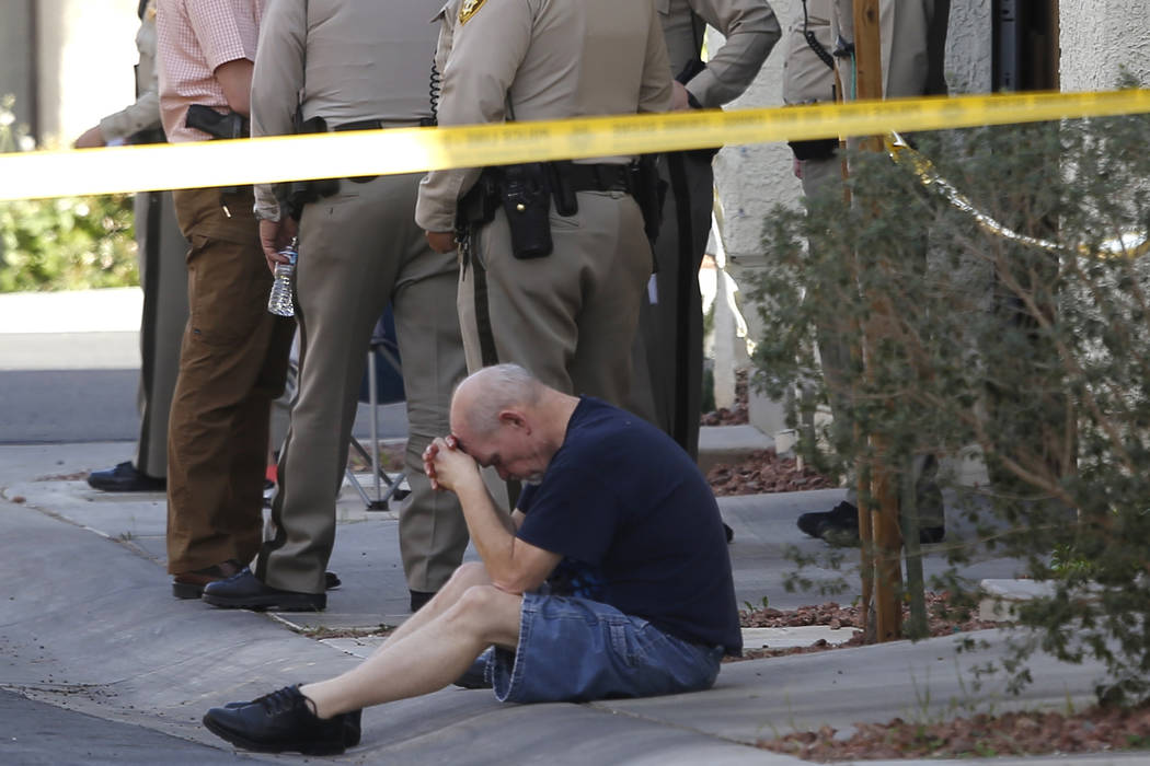 A man sits with his head down where Las Vegas Metropolitan police officers are investigating a shooting near the 10200 block of Yarmouth Sea Ct. on Friday, March 17, 2017, in Las Vegas. (Christian ...