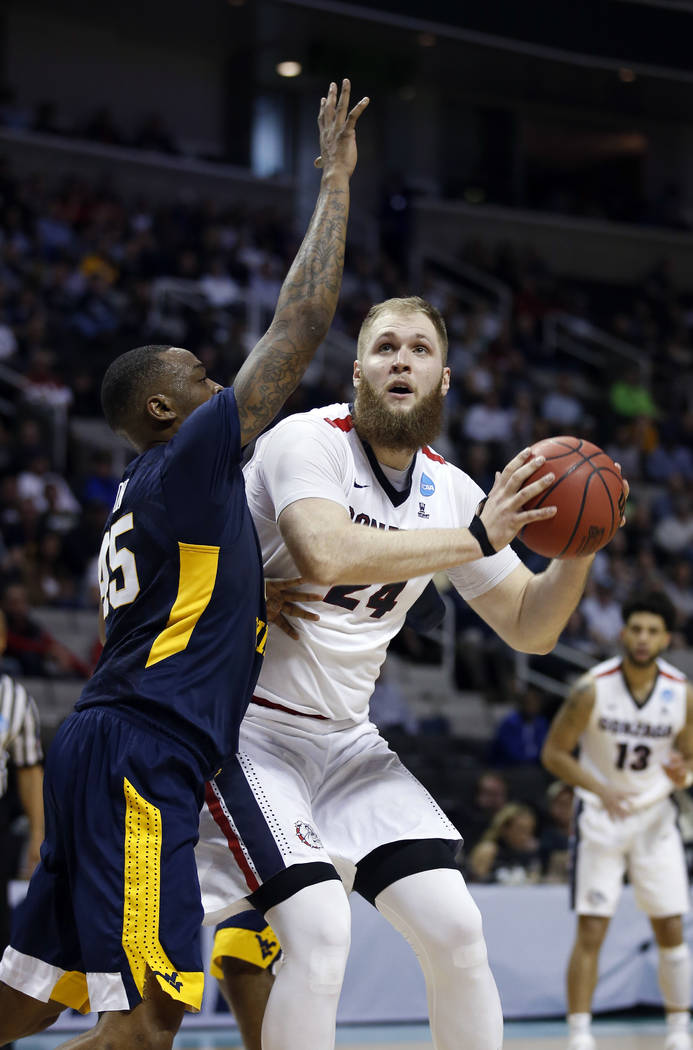 Gonzaga center Przemek Karnowski (24) is defended by West Virginia forward Elijah Macon during the first half of an NCAA Tournament college basketball regional semifinal game Thursday, March 23, 2 ...