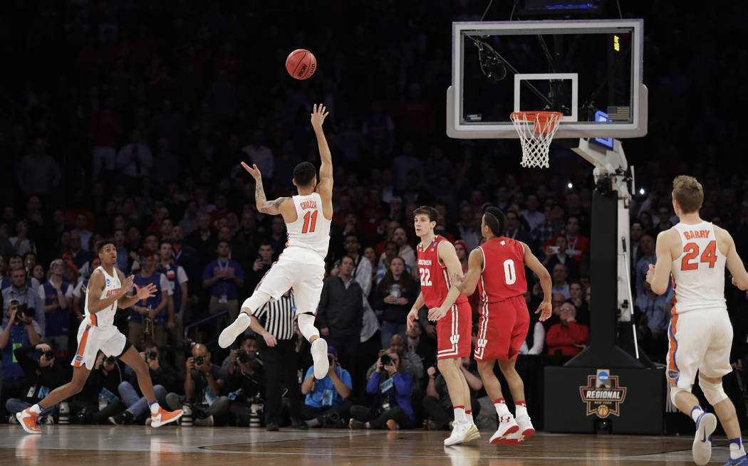 Florida guard Chris Chiozza (11) puts up a last second 3-point shot to score the game-winning points against Wisconsin in overtime of an East Regional semifinal game of the NCAA men's college bask ...
