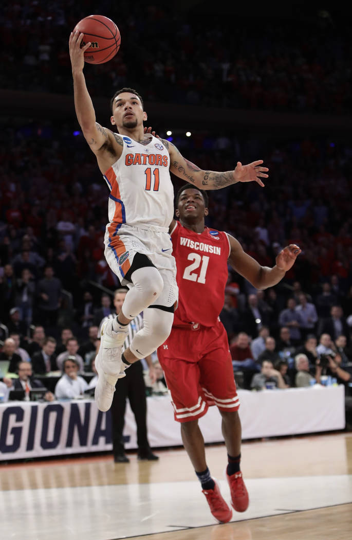 Florida guard Chris Chiozza (11) goes up for a shot against Wisconsin guard Khalil Iverson (21) in overtime of an East Regional semifinal game of the NCAA men's college basketball tournament, Satu ...