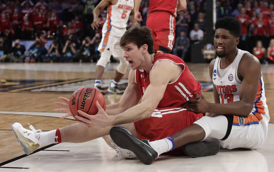 Wisconsin forward Ethan Happ (22) looks to get a pass off against Florida forward Kevarrius Hayes (13) in overtime of an East Regional semifinal game of the NCAA men's college basketball tournamen ...