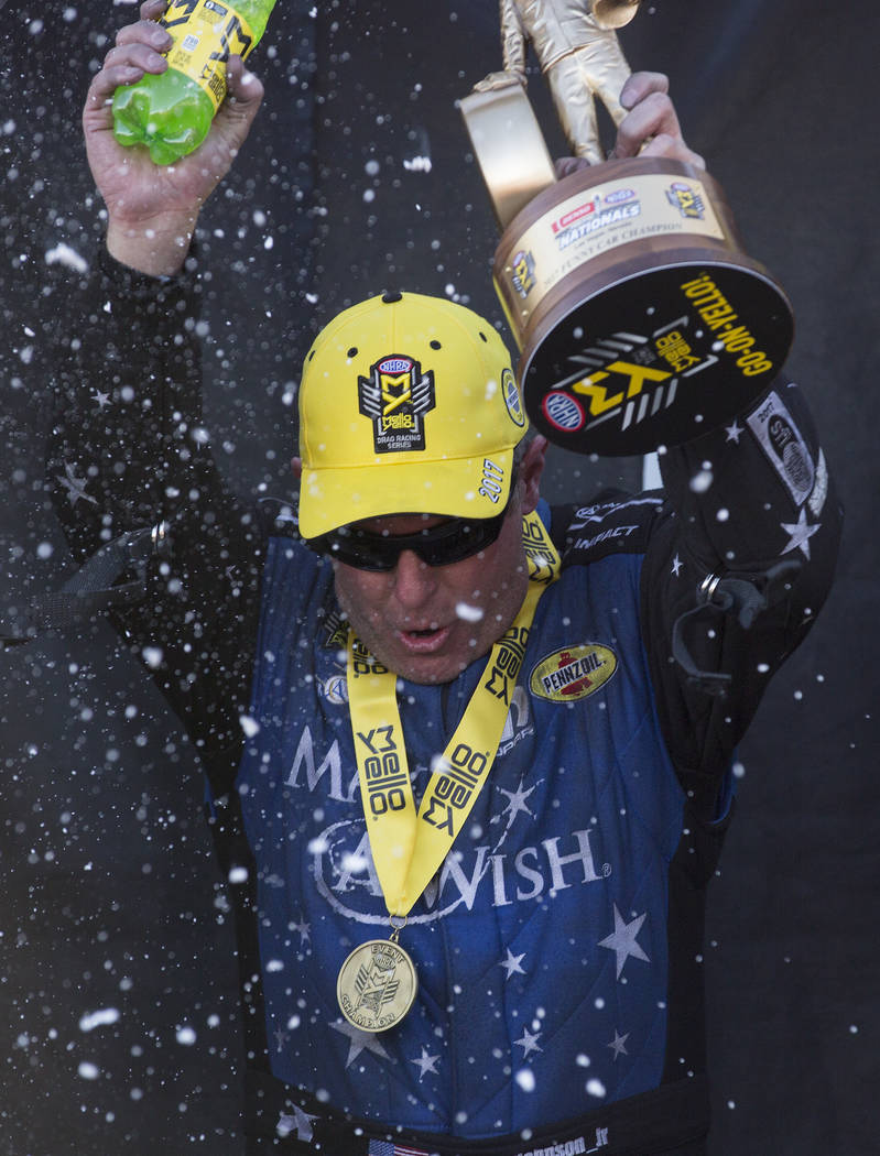 Funny Car driver Tommy Johnson Jr. holds up his trophy after his win at the DENSO Spark Plugs NHRA Nationals at The Strip at Las Vegas Motor Speedway on Sunday, April 2, 2017, in Las Vegas. (Bridg ...