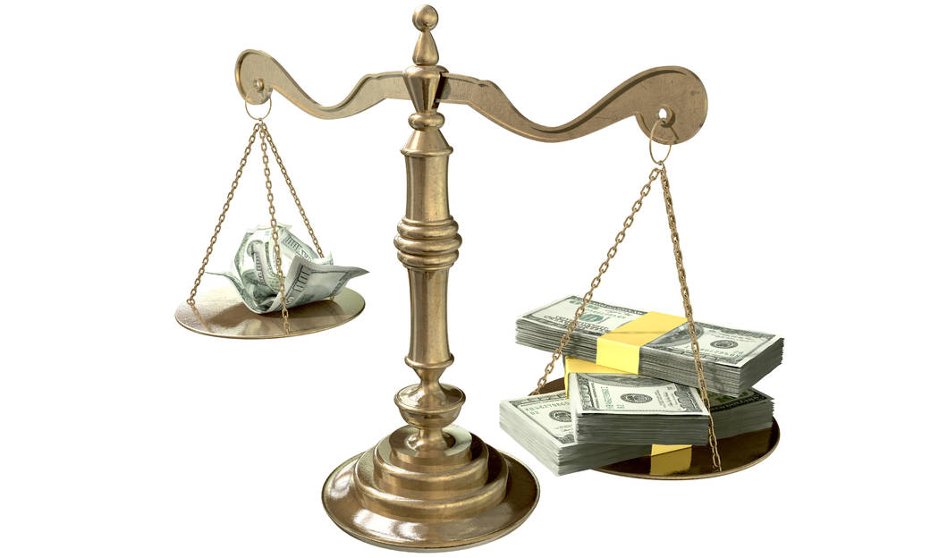 An old school bronze justice scale with stacks of us dollar money on one side and a few crumpled notes on the other representing the inequality in the income gap an isolated white background