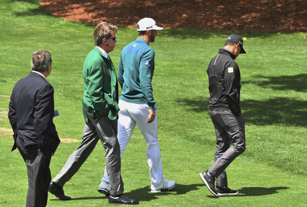 Dustin Johnson, center, walks off the 1st tee after deciding not to play in the opening round of the Masters golf tournament at the Augusta National Golf Club in Augusta, Ga., Thursday, April 6, 2 ...