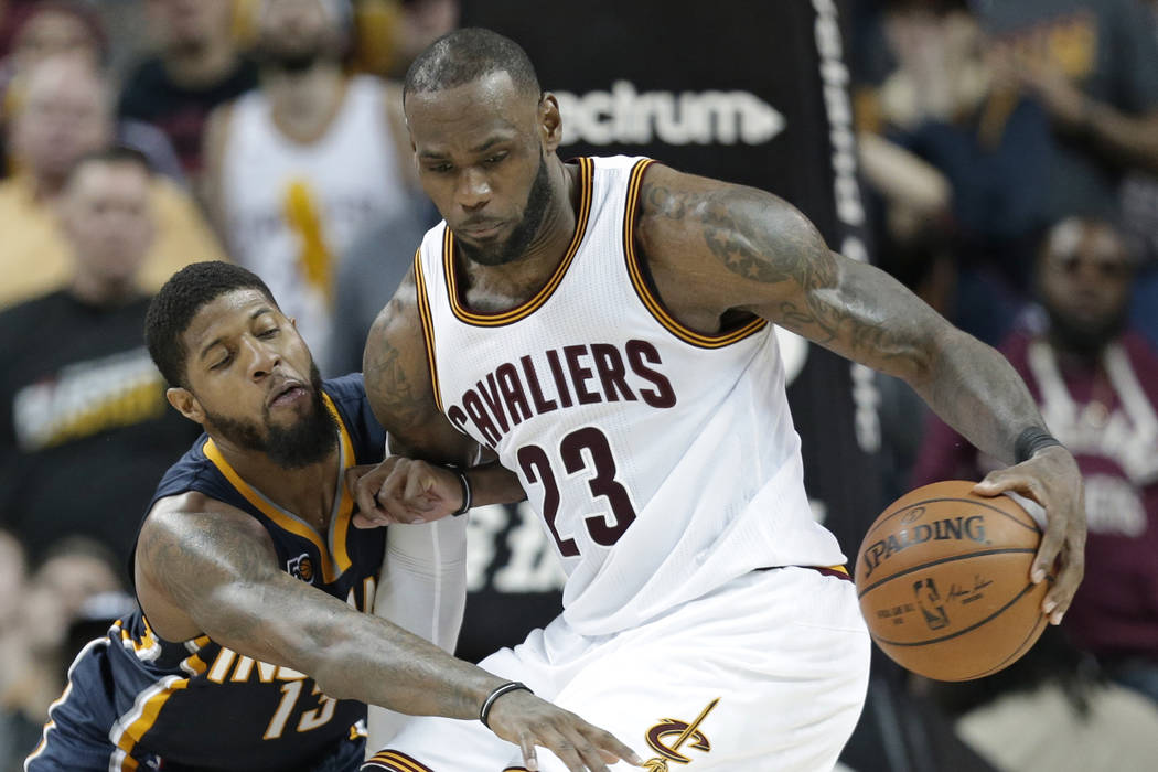 Indiana Pacers' Paul George, left, reaches for the ball as Cleveland Cavaliers' LeBron James drives to the basket in overtime during an NBA basketball game, Sunday, April 2, 2017, in Cleveland. Th ...