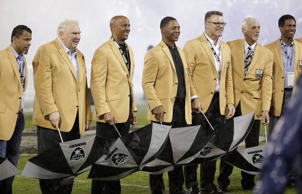 Hall of Famers Rod Woodson, from left, John Madden, James Lofton, Marcus Allen, Howie Long, Ray Guy, and Mike Haynes stand during a Hall of Fame ceremony for Guy during halftime of an NFL football ...