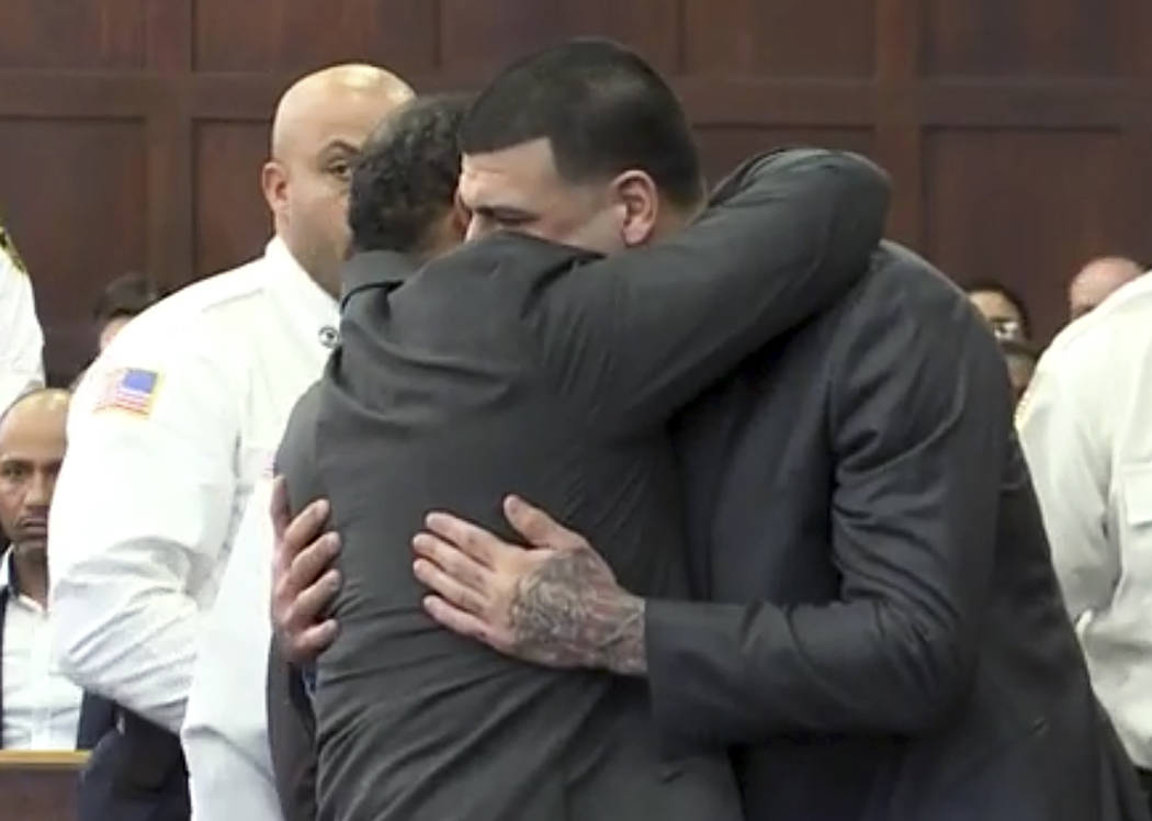In this still image from video, Aaron Hernandez, center, is hugged by defense attorney Ronald Sullivan, Friday, April 14, 2017, in court in Boston, after being found not guilty of murder in the 20 ...