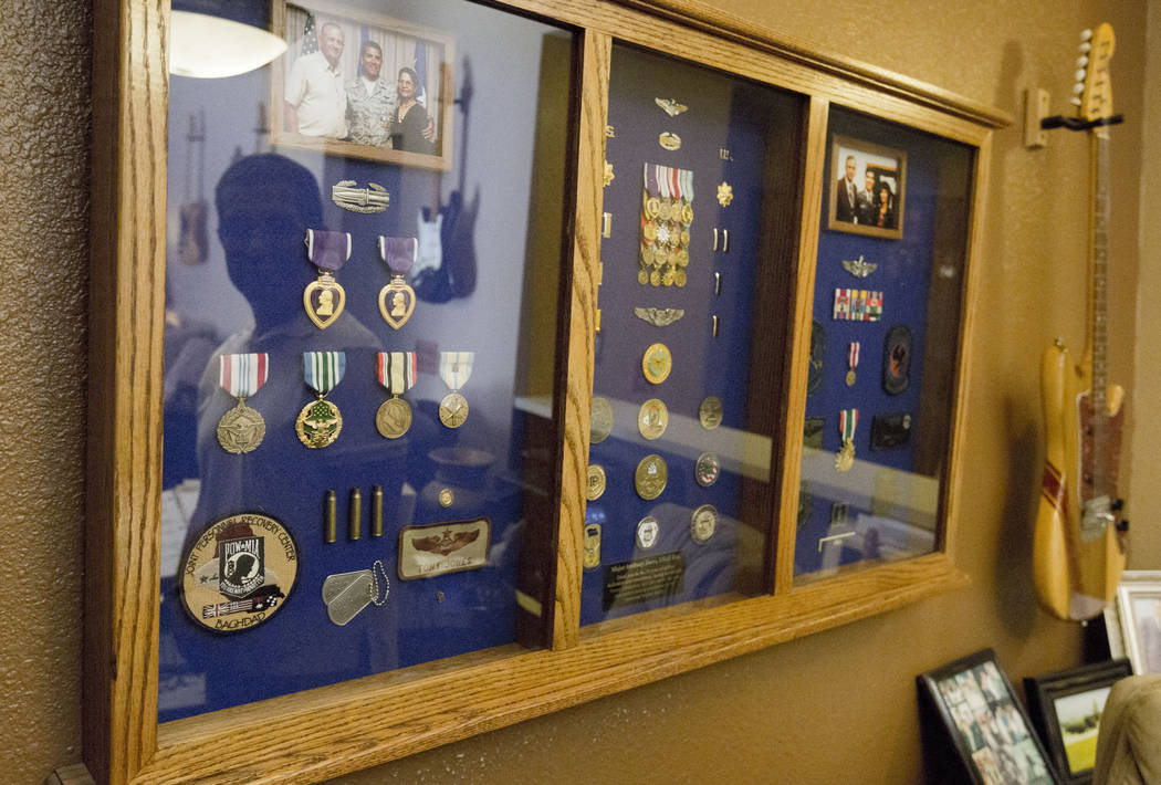 Author and former Air Force major Anthony Jones suffers from major brain injuries from Iraq, looks at his shadow box of medals and memorabilia from his time in service in his home in Las Vegas, We ...