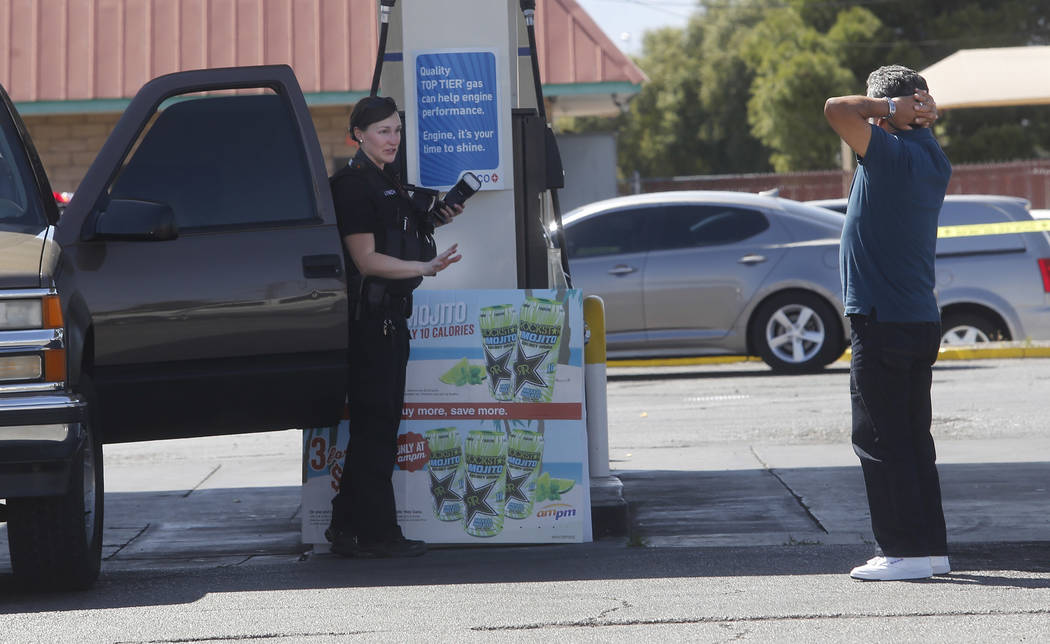 A crime scene investigator attempts to calm a man as he reacts after arriving to a crime scene where a stabbing occurred at the Arco gas station located on Bonanza Rd. and N Lamb Blvd. on Wednesda ...