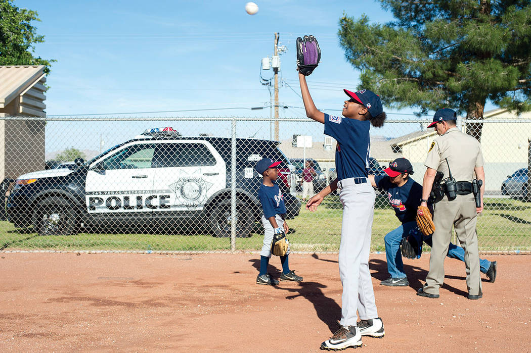 Alayja Grayson, 11, warms up with teammates as Metro officer Dave Shive coaches them before a Bolden Little League game Thursday at Doolittle Field. Bolden Little League, co-founded by Mario Berla ...