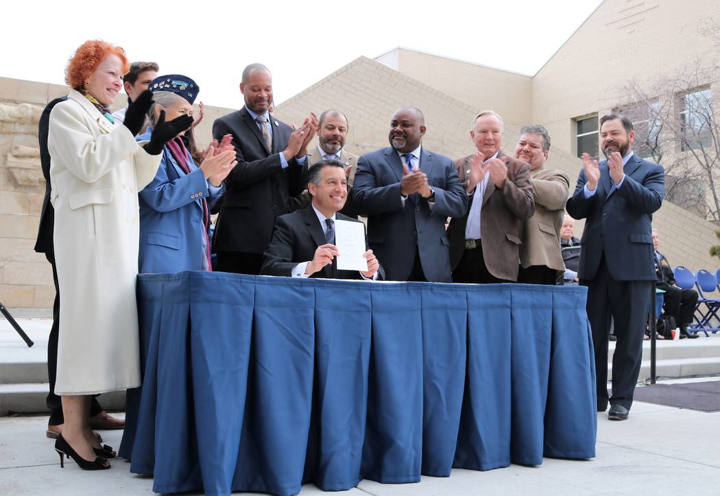 Legislators applaud as Gov. Brian Sandoval holds up SVB58 after signing it during a ceremony kicking off 2017 Veterans and Military Day at the Legislature, Wednesday, March 15, 2017. (Victor Joeck ...