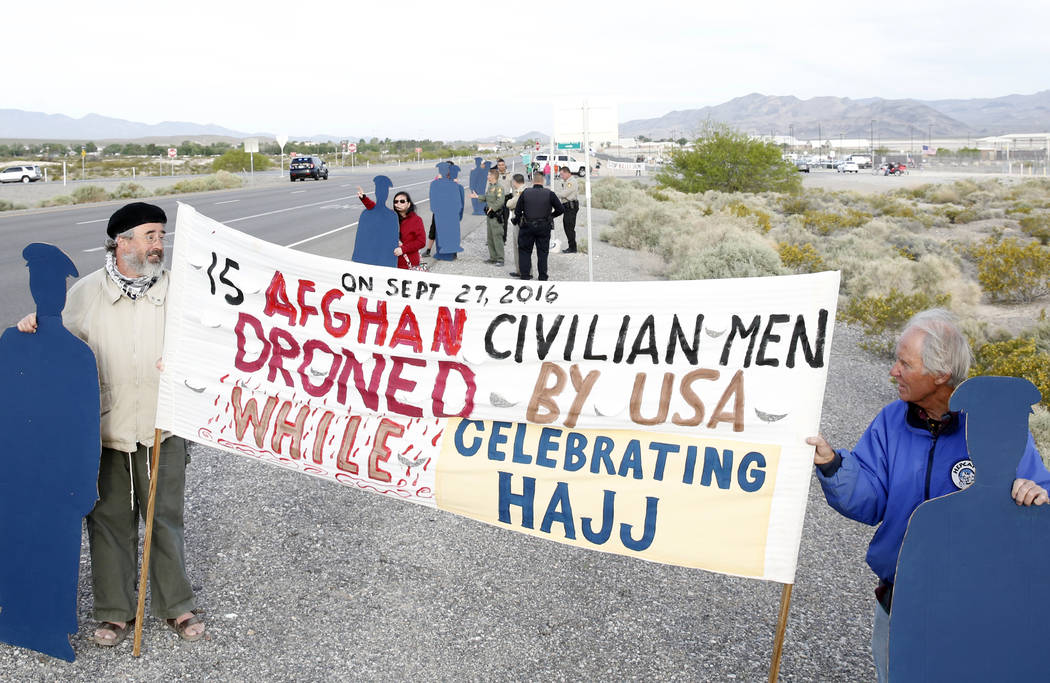 Anti-drone warfare protesters, Brian Terrell, left, and Dennis DuVall hold life-size cardboard human figures outside Creech Air Force Base at Indian Springs on Monday, April 24, 2017, to honor the ...