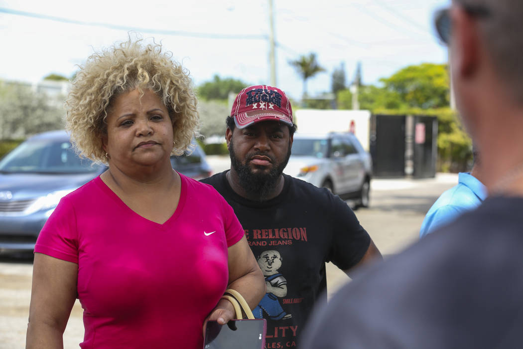 Miami-Dade Police Detective Daniel Garcia, far right, speaks with Valentina De Leon and her husband before conducting an operation to remove squatters from their house in Miami on Tuesday, April 1 ...